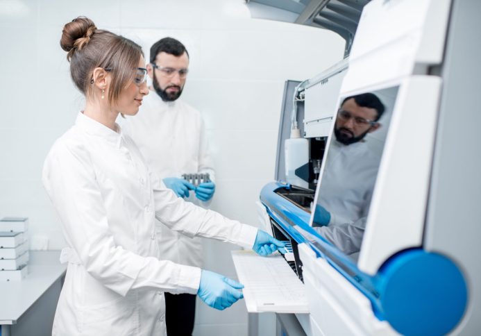 Laboratory assistants in unifrom working with professional medical analizer at the laboratory